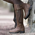 Dark brown knee-high leather riding boots, worn